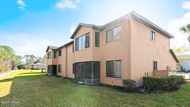 rear view of property with a yard and a sunroom