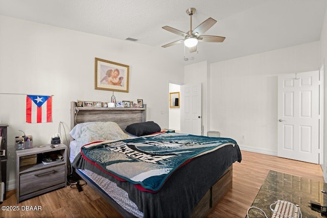 bedroom featuring hardwood / wood-style floors, a textured ceiling, vaulted ceiling, and ceiling fan