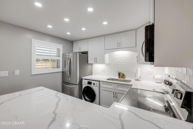 kitchen featuring a sink, freestanding refrigerator, backsplash, washer / clothes dryer, and recessed lighting