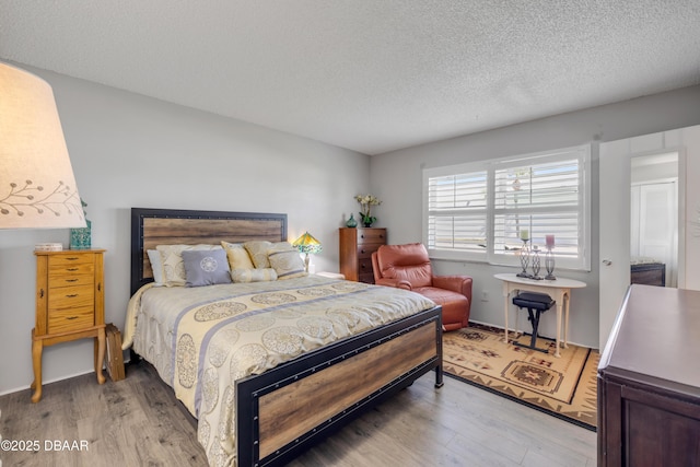 bedroom with light wood-type flooring and a textured ceiling