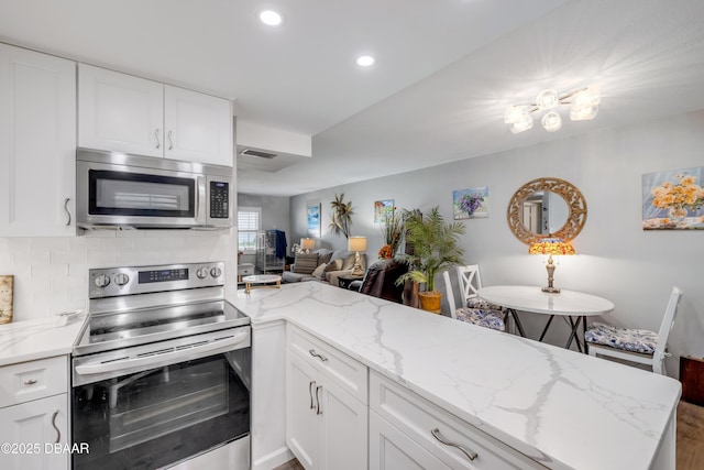 kitchen with recessed lighting, white cabinets, stainless steel appliances, backsplash, and light stone countertops