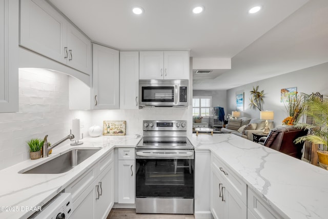 kitchen with recessed lighting, stainless steel appliances, visible vents, a sink, and white cabinetry