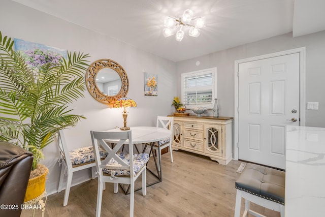 dining space with baseboards, a chandelier, and light wood-type flooring