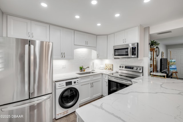 kitchen with stainless steel appliances, a sink, visible vents, recessed lighting, and washer / dryer