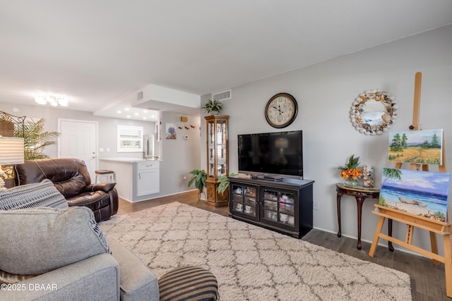 living room with wood finished floors, visible vents, and baseboards