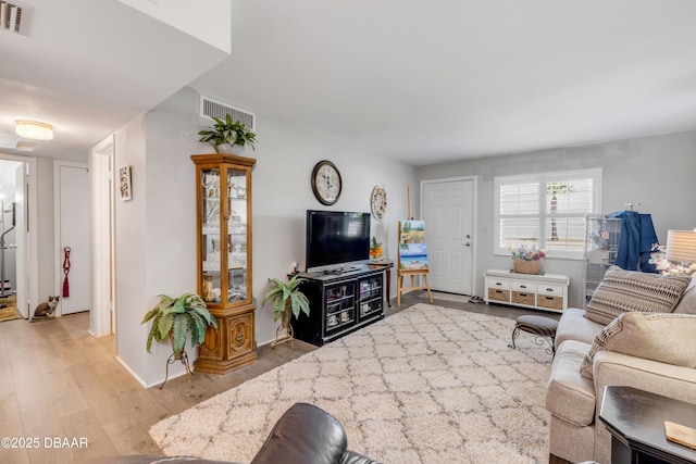 living room with wood finished floors, visible vents, and baseboards