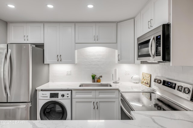 kitchen featuring white cabinets, washer / dryer, stainless steel appliances, and a sink