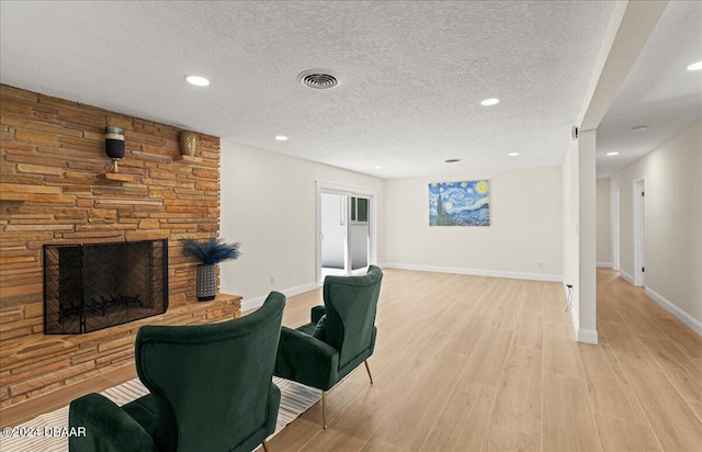 living room with a fireplace, light hardwood / wood-style floors, and a textured ceiling