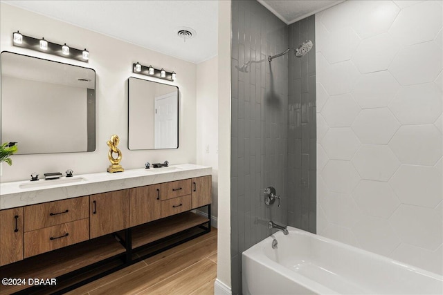 bathroom featuring wood-type flooring, tiled shower / bath combo, and vanity