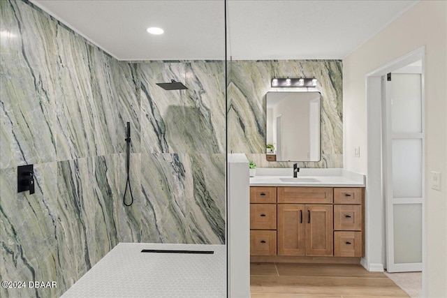 bathroom featuring hardwood / wood-style floors, walk in shower, vanity, and tile walls