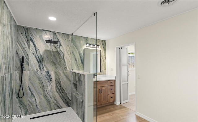 bathroom with walk in shower, a textured ceiling, wood-type flooring, vanity, and tile walls