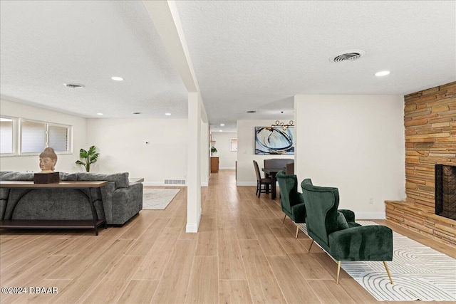 living room with a fireplace, a textured ceiling, and light hardwood / wood-style flooring