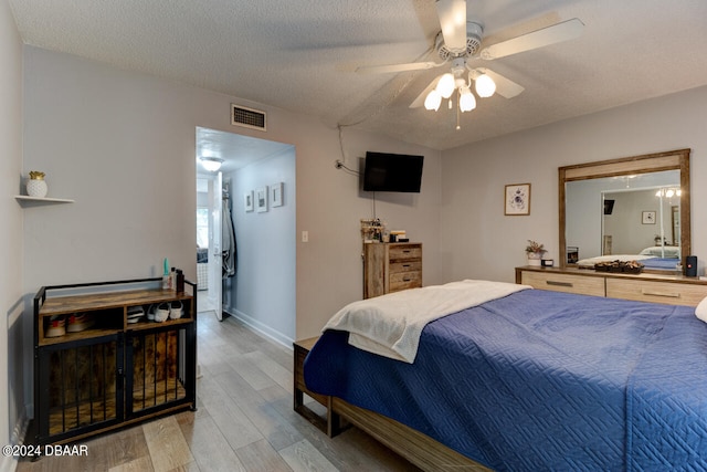 bedroom featuring light hardwood / wood-style floors, ceiling fan, and a textured ceiling