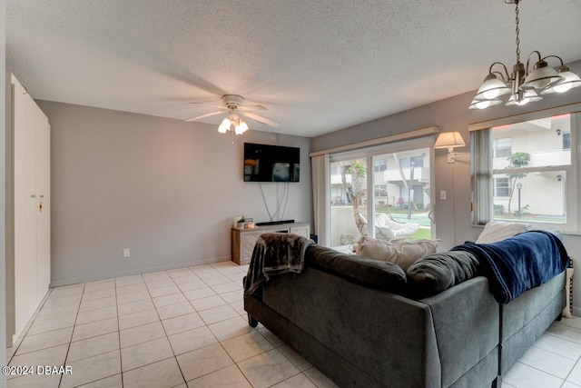 tiled living room featuring ceiling fan with notable chandelier and a textured ceiling