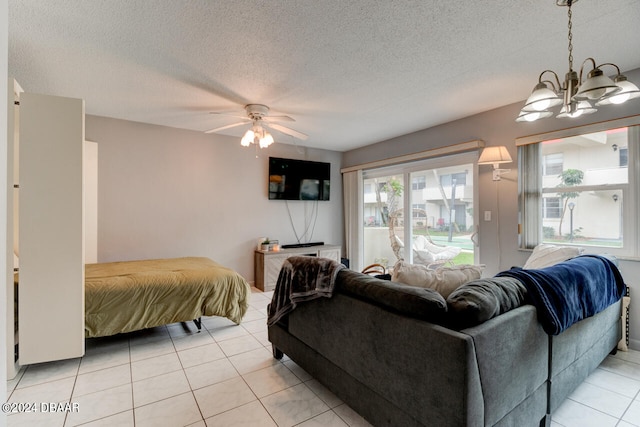 living room with light tile patterned flooring, ceiling fan with notable chandelier, and a textured ceiling