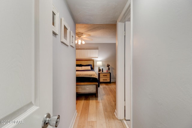 hall with light wood-type flooring and a textured ceiling