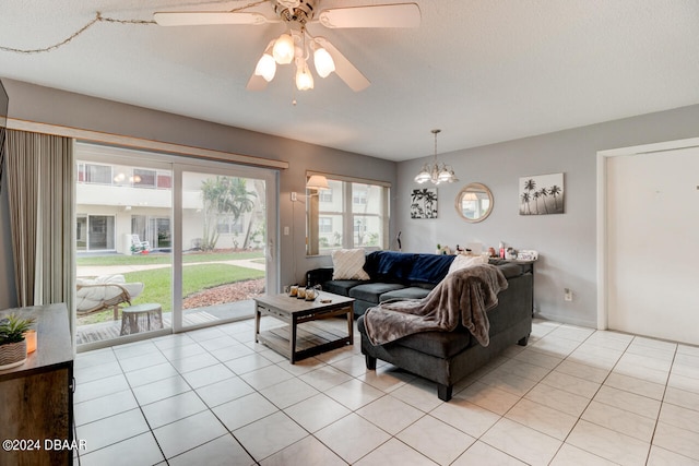 living room with a textured ceiling, light tile patterned flooring, and ceiling fan with notable chandelier