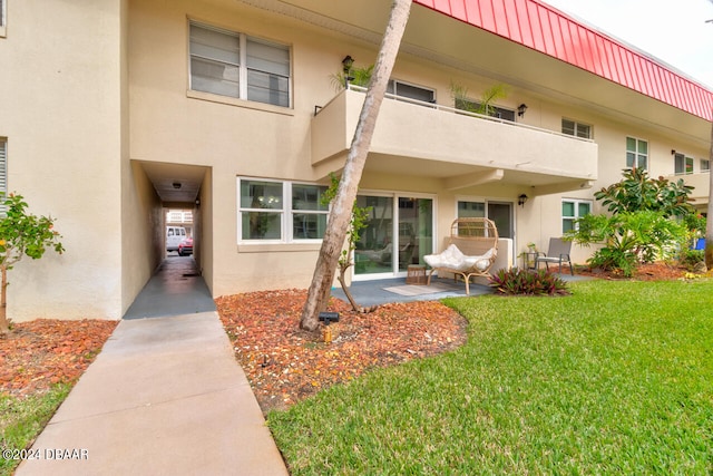 doorway to property featuring a lawn and a balcony