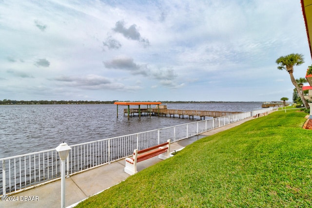 view of dock featuring a lawn and a water view