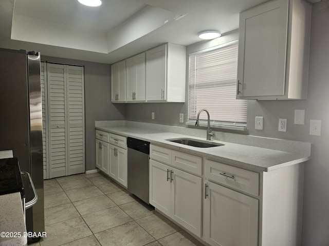 kitchen with dishwasher, light countertops, a sink, and white cabinetry