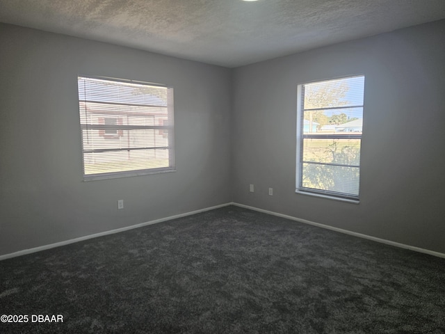 spare room with baseboards, a textured ceiling, and dark carpet