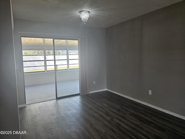 unfurnished room with dark wood finished floors, baseboards, a chandelier, and a textured ceiling
