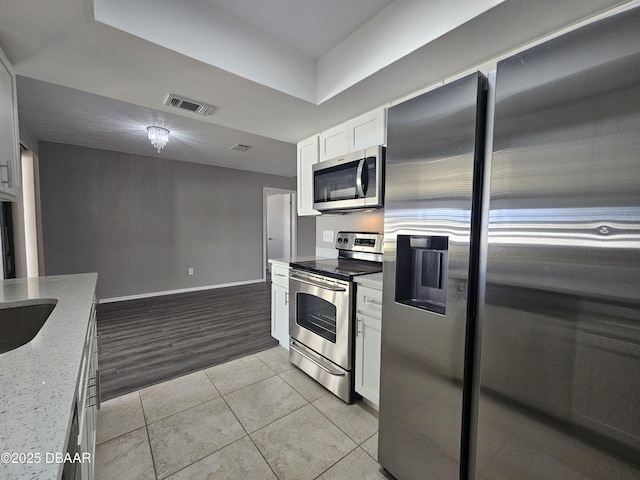 kitchen with white cabinetry, baseboards, visible vents, light stone countertops, and appliances with stainless steel finishes