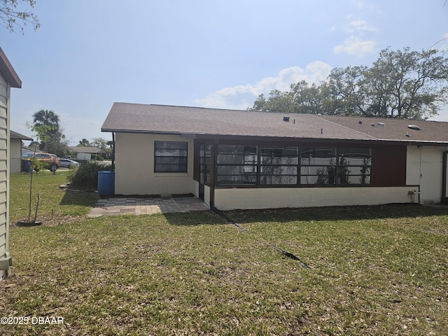 back of property featuring a shingled roof, a yard, and concrete block siding