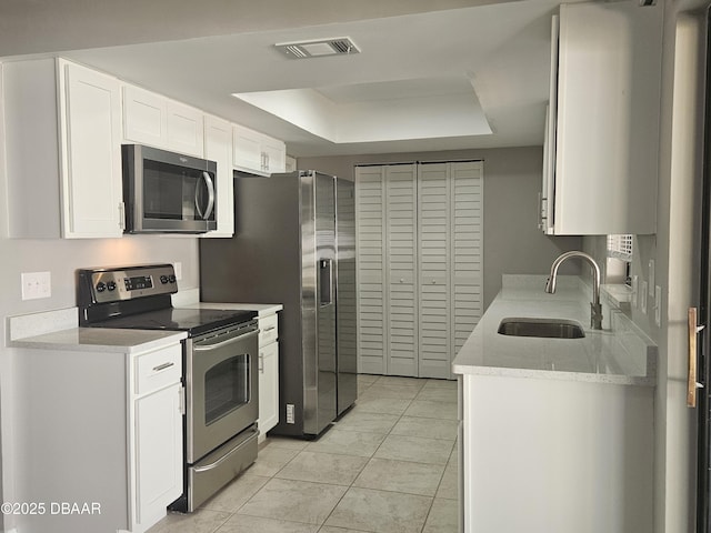 kitchen featuring a sink, a raised ceiling, white cabinetry, appliances with stainless steel finishes, and visible vents