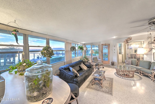 living room featuring ceiling fan, plenty of natural light, and a textured ceiling