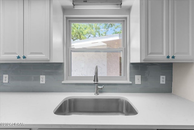 kitchen with sink, white cabinets, and backsplash