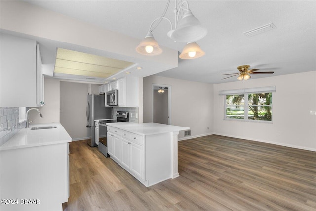 kitchen with white cabinets, stainless steel appliances, ceiling fan, sink, and decorative light fixtures