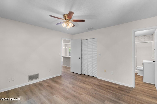 unfurnished bedroom featuring ensuite bath, ceiling fan, light hardwood / wood-style flooring, and a closet