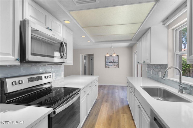 kitchen featuring sink, decorative light fixtures, white cabinetry, tasteful backsplash, and appliances with stainless steel finishes