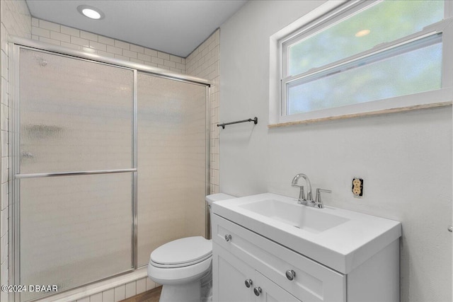 bathroom featuring a shower with shower door, vanity, and toilet