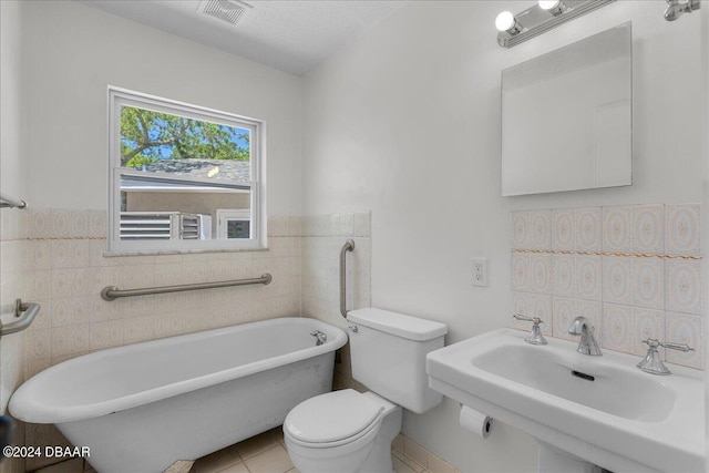 bathroom with sink, tile walls, toilet, and a bathing tub