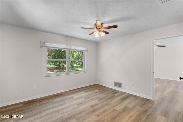 spare room with a textured ceiling and light hardwood / wood-style flooring