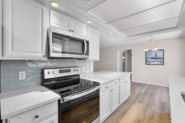 kitchen featuring pendant lighting, decorative backsplash, an inviting chandelier, white cabinets, and appliances with stainless steel finishes