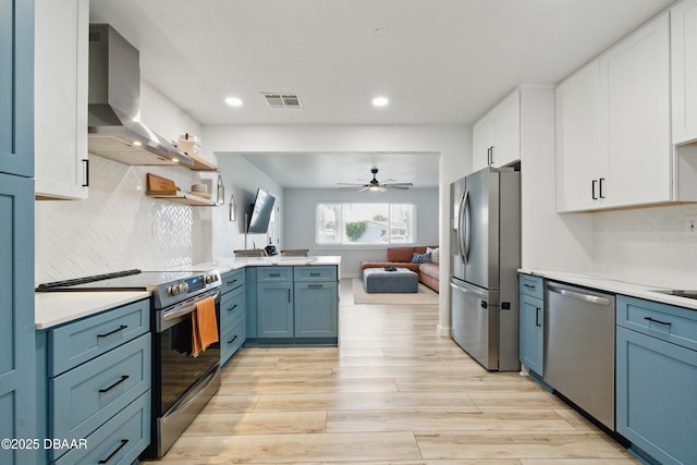 8 Camellia Dr, Ormond Beach, FL 32176 - kitchen with wall chimney range hood, ceiling fan, appliances with stainless steel finishes, light wood-style floors, and visible vents