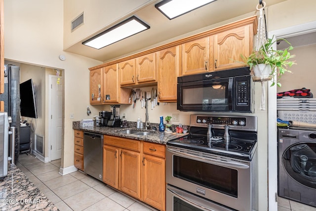 kitchen featuring visible vents, a sink, dark stone countertops, washer / dryer, and stainless steel appliances