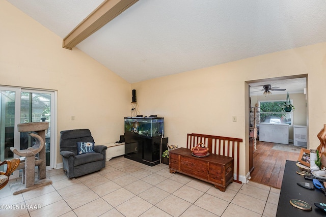 living area with a healthy amount of sunlight, ceiling fan, lofted ceiling with beams, and light tile patterned flooring