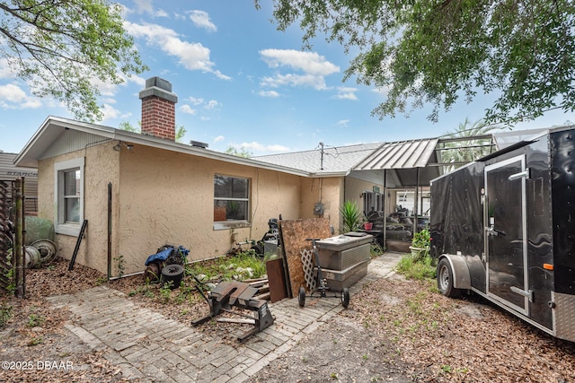 back of property featuring a lanai, a chimney, and stucco siding