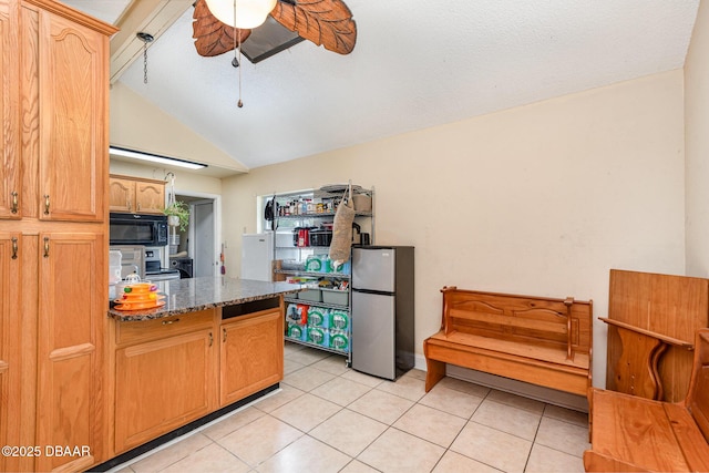 kitchen featuring freestanding refrigerator, black microwave, ceiling fan, light tile patterned floors, and vaulted ceiling