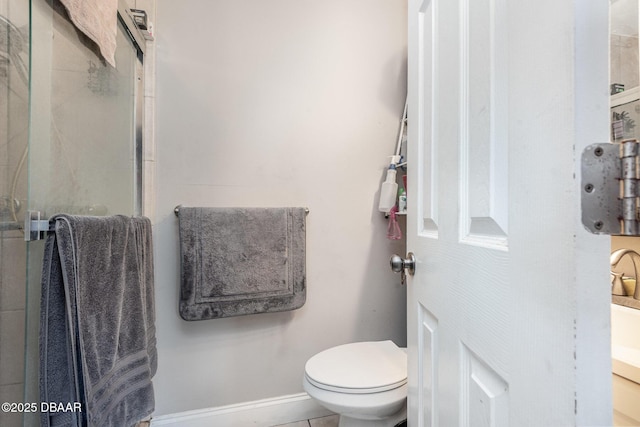 bathroom featuring toilet, baseboards, a shower stall, and tile patterned flooring