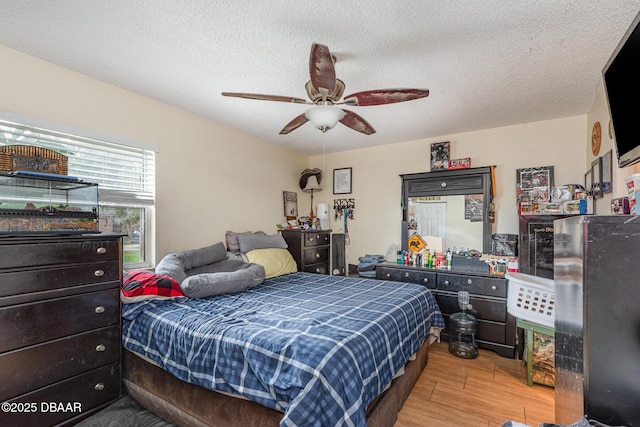 bedroom with a textured ceiling, a ceiling fan, and wood finished floors
