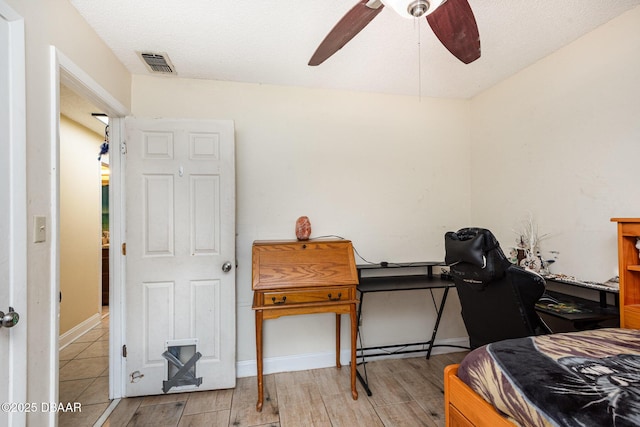 bedroom featuring baseboards, a ceiling fan, wood finished floors, and visible vents
