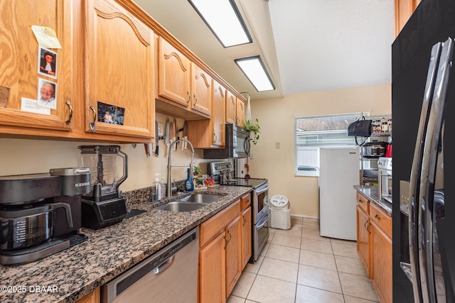 kitchen with light tile patterned floors, a sink, black appliances, and dark stone countertops