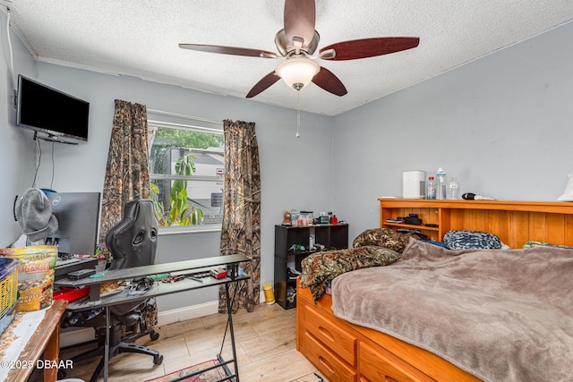 bedroom featuring a ceiling fan, a textured ceiling, baseboards, and light wood-style floors