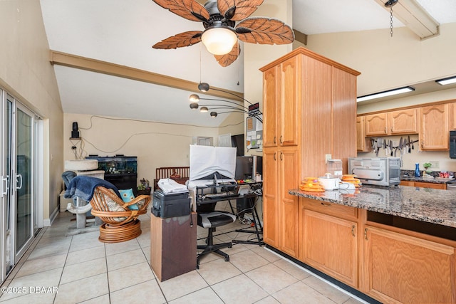 kitchen with light tile patterned flooring, ceiling fan, lofted ceiling with beams, dark stone counters, and a toaster