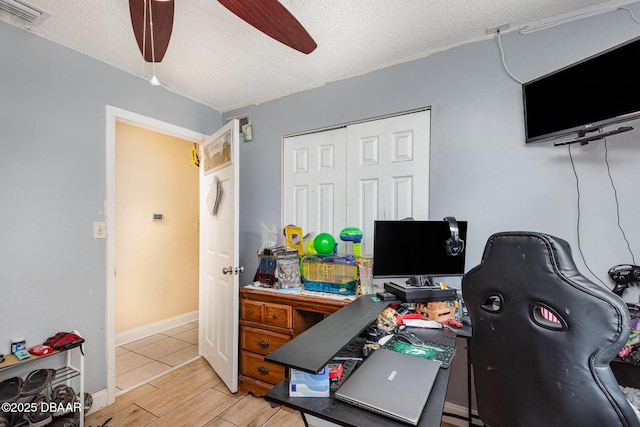 office space with a textured ceiling, visible vents, ceiling fan, and light wood-type flooring